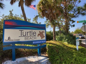 Señal de Turtle Beach en el condado de Sarasota, con un gráfico de tortuga marina y la dirección 8918 Midnight Pass Rd.