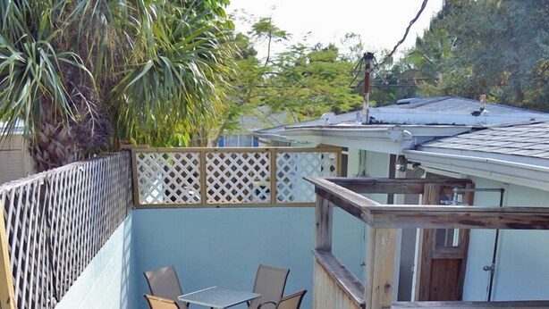 A patio area with a table and chairs, a grill, and a wooden fence. - One Ocean - A (Siesta Key)