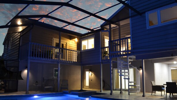 A two-story house with a swimming pool, a balcony, and a staircase leading to the upper floor. - The Treehouse (Siesta Key)