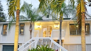 A two-story house with a white exterior, a white staircase, and palm trees. - Shell Beach Home (Siesta Key)