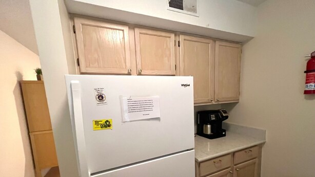 A compact kitchen with a white refrigerator, wooden cabinets, and a coffee maker on the counter. - Top Floor Private Villa Close to Everything Amenity Cards Available 1819 (Seabrook Island)