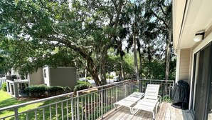 A wooden deck with two white lounge chairs and a metal chair, surrounded by a metal railing. - Top Floor Private Villa Close to Everything Amenity Cards Available 1819 (Seabrook Island)