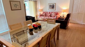 A dining area with a glass-top table and wooden chairs, a floral sofa, and a lamp on a side table. - Top Floor Private Villa Close to Everything Amenity Cards Available 1819 (Seabrook Island)