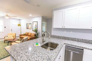 A modern kitchen with granite countertops, a stainless steel sink, and a built-in dishwasher. - Trendy Home by Jet Skis, Parks & Art Hotspots (Sarasota)