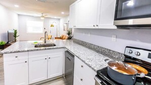 Una cocina moderna con armarios blancos, encimera de granito, estufa y microondas.