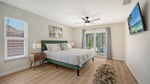 A bedroom with a bed, nightstands, a ceiling fan, a painting, and a view of a pool through a sliding glass door. - Modern Spacious 3 Bedroom, 2 Bathroom Private Pool Home in Sarasota Near Siesta Key (Sarasota)