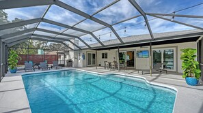 A covered swimming pool with clear blue water, surrounded by lounge chairs and a patio area with a view of the sky. - Modern Spacious 3 Bedroom, 2 Bathroom Private Pool Home in Sarasota Near Siesta Key (Sarasota)