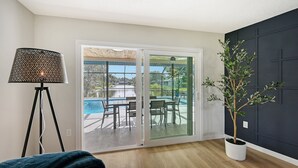 A room with a sliding glass door leading to an outdoor pool area, a potted plant, and a floor lamp. - Modern Spacious 3 Bedroom, 2 Bathroom Private Pool Home in Sarasota Near Siesta Key (Sarasota)