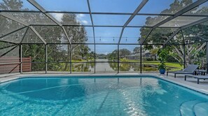 A pool with a clear view of a lake, surrounded by a covered area with a metal frame and string lights. - Modern Spacious 3 Bedroom, 2 Bathroom Private Pool Home in Sarasota Near Siesta Key (Sarasota)
