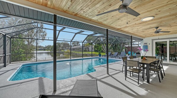 A covered swimming pool with a glass enclosure, ceiling fans, and a patio area with seating. - Modern Spacious 3 Bedroom, 2 Bathroom Private Pool Home in Sarasota Near Siesta Key (Sarasota)