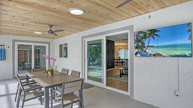 A modern interior with a wooden ceiling, a dining area with a table and chairs, and a large window with a view of the outdoors. - Modern Spacious 3 Bedroom, 2 Bathroom Private Pool Home in Sarasota Near Siesta Key (Sarasota)