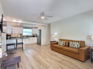 A modern apartment with a kitchen, a living area with a sofa and a coffee table, and a ceiling fan. - Siesta Heron 4 (Siesta Key)