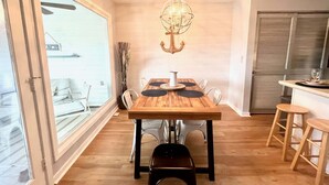 Un comedor con una mesa de madera, sillas, una araña y vistas a través de un ventanal grande.