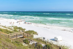 A beach with a wooden walkway leading to a white building, likely a lifeguard station. - Serenity Now (Santa Rosa Beach)