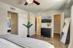 A bedroom with a bed, a dresser, a potted plant, a painting, and a ceiling fan. - Osborn (Scottsdale)