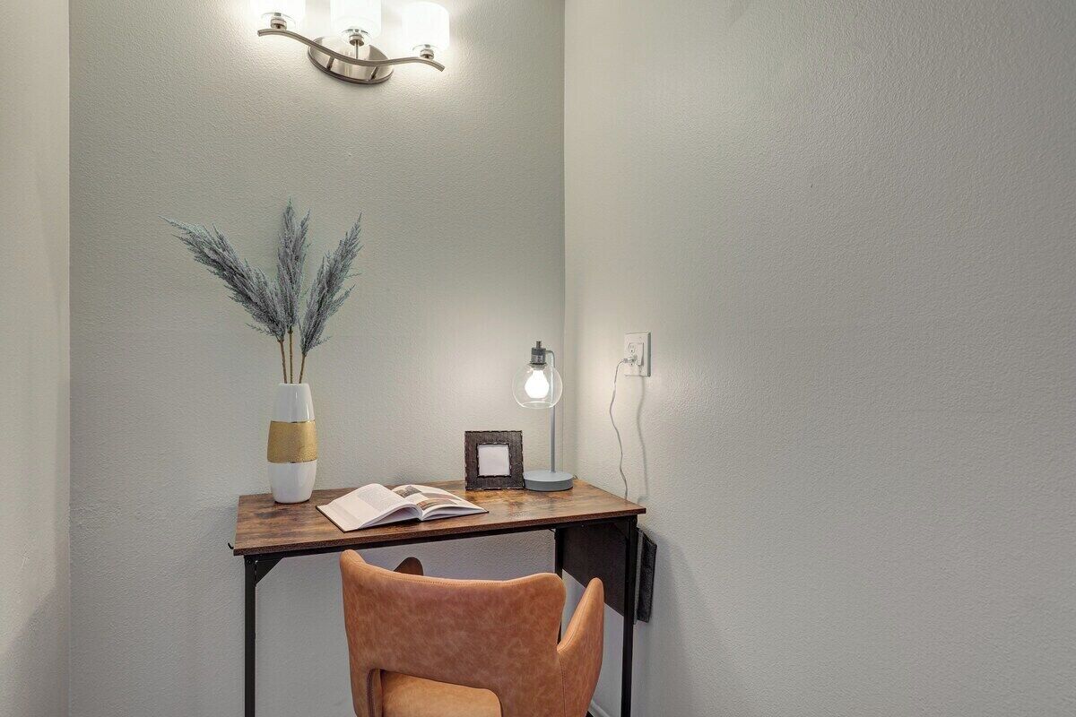 Een werkhoek met een bureau, stoel, lamp en decoratieve objecten.