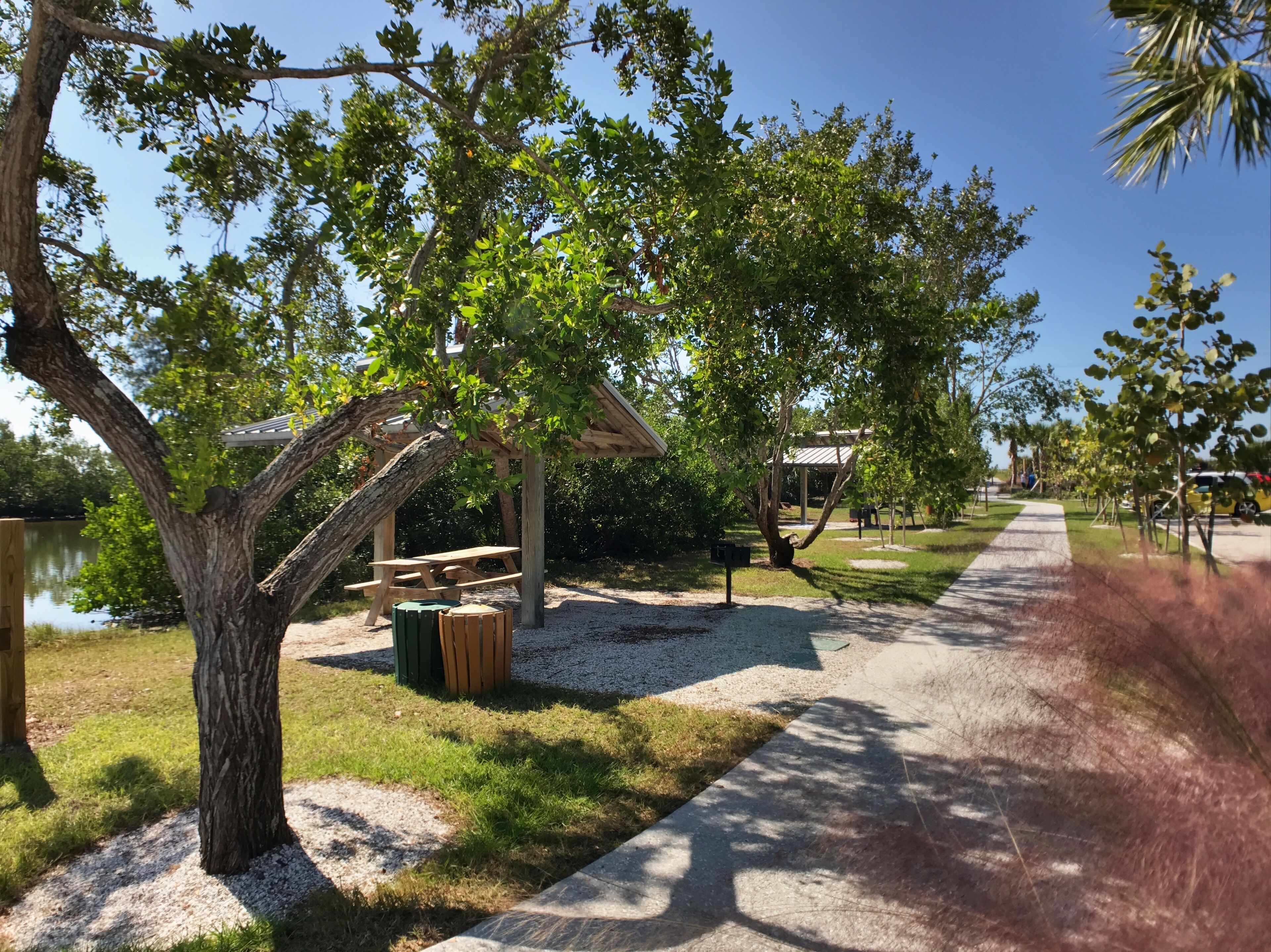 A park with a picnic table, a wooden shelter, and a pathway.