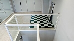 Ein modernes Zimmer mit Schachbrettfußboden, einem Glastisch und einer weißen Treppe.