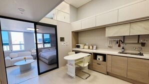 Eine moderne Küche mit Essbereich, einer Küchenzeile und einem Wohnbereich mit Sofa und Blick auf die Stadt.