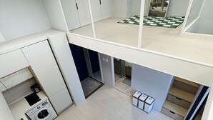 Ein kompaktes, modernes Apartment mit einer Küchenzeile, einer kleinen Essecke und einem Schachbrettfußboden.