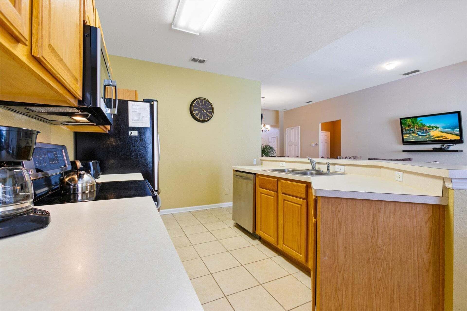 A kitchen with a stove, coffee maker, and a clock on the wall.