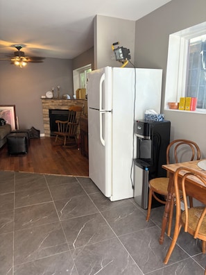 A compact kitchen with a refrigerator, a coffee maker, and a dining area with a table and chairs.