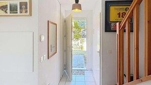 Ein Flur mit Deckenleuchte, gerahmten Bildern und einer Tür zum Ausgang.