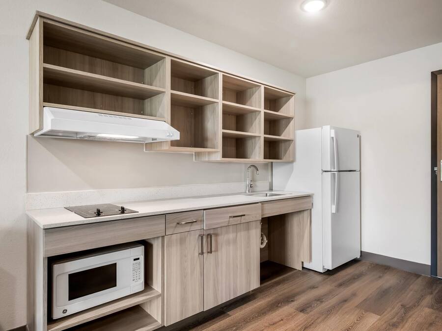 A kitchen with a microwave, stove, sink, and a refrigerator.