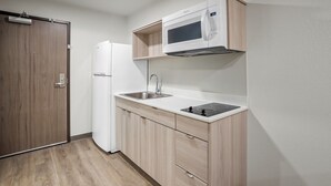 Cocina compacta con microondas, lavamanos y armarios empotrados.