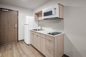 Una cocina compacta con microondas, fregadero y horno empotrado.