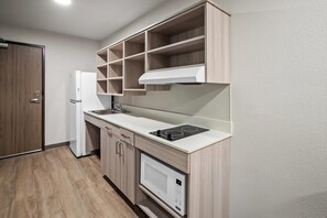 Eine kleine Küche mit einer eingebauten Mikrowelle, einem Herd und einem Kühlschrank.