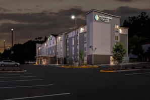 Un hôtel à plusieurs étages, sur lequel on peut lire l’inscription « Woodspring Suites ».