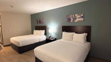 Una habitación de hotel con dos camas, una mesita de noche y una obra de arte en la pared.