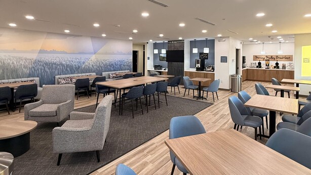 A modern dining area with multiple tables and chairs, a coffee station, and a mural on the wall. - Sleep Inn - Oklahoma City Airport (Oklahoma City)