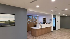 A reception area with a wooden reception desk, a wall-mounted TV, and a decorative partition with cut-out patterns. - Sleep Inn - Oklahoma City Airport (Oklahoma City)