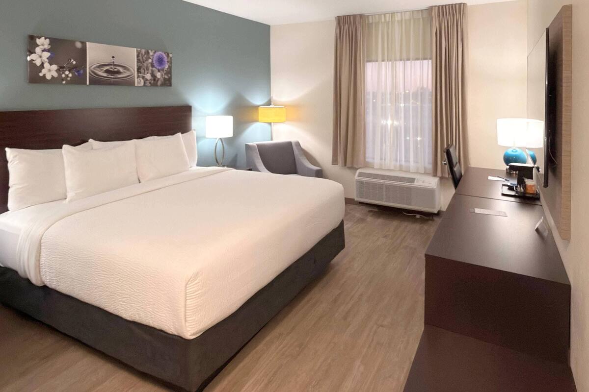 Une chambre d’hôtel avec un grand lit, un bureau, une chaise, un appareil de climatisation et un téléviseur.
