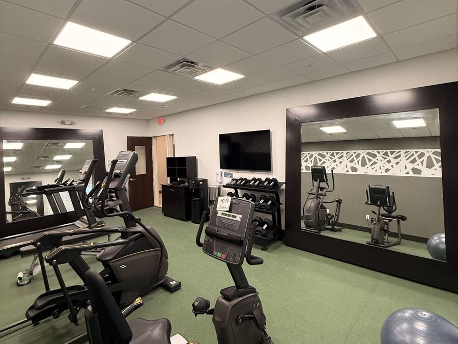 A gym with treadmills, elliptical machines, and a mirrored wall.
