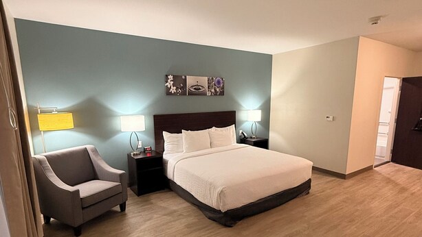 A modern hotel room with a large bed, a bedside table with a lamp, a chair, and a wall-mounted artwork. - Sleep Inn - Oklahoma City Airport (Oklahoma City)