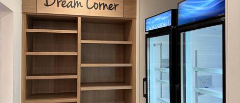 A room with a wooden shelving unit labeled "Dream Corner" and two ice dispensers.