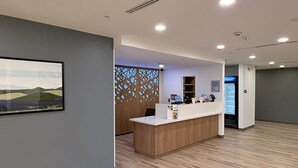 A reception area with a wooden reception desk, a wall-mounted screen, and a decorative partition with cut-out patterns. - Mainstay Suites - Oklahoma City Airport (Oklahoma City)