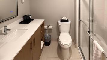 A modern bathroom with a white sink, a toilet, and a glass shower enclosure.