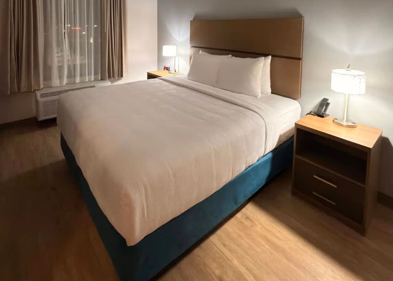A hotel room with a bed, bedside tables, a lamp, and a nightstand.
