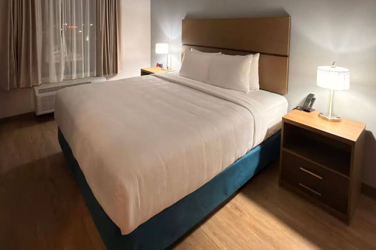 Une chambre d’hôtel avec un lit, des tables de chevet, une lampe et une petite table.