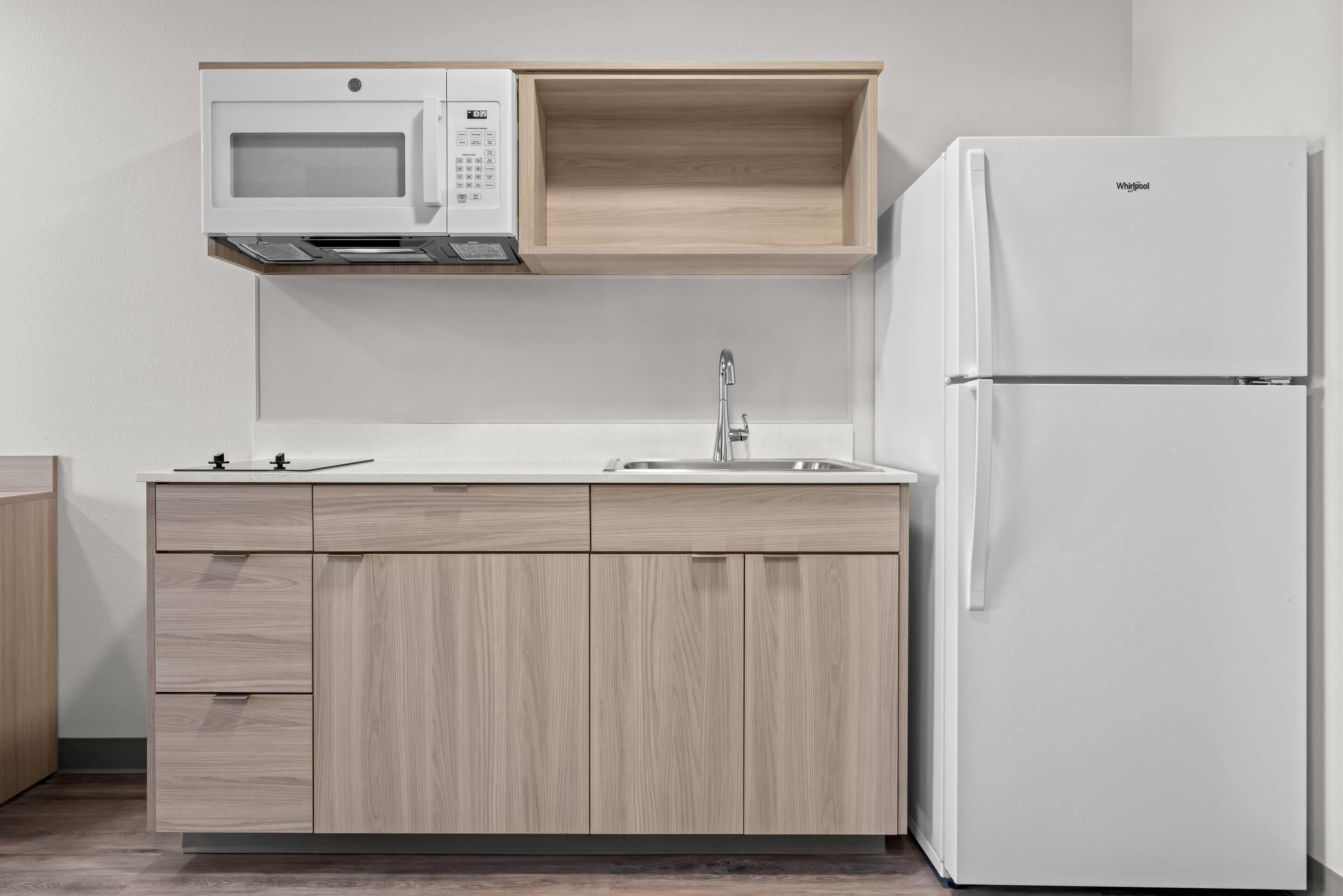 A kitchen with a microwave, sink, and refrigerator.