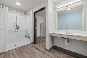 A modern bathroom with a shower, toilet, and sink, and a mirror above the sink. - Woodspring Suites Manteca - Stockton South (Manteca)