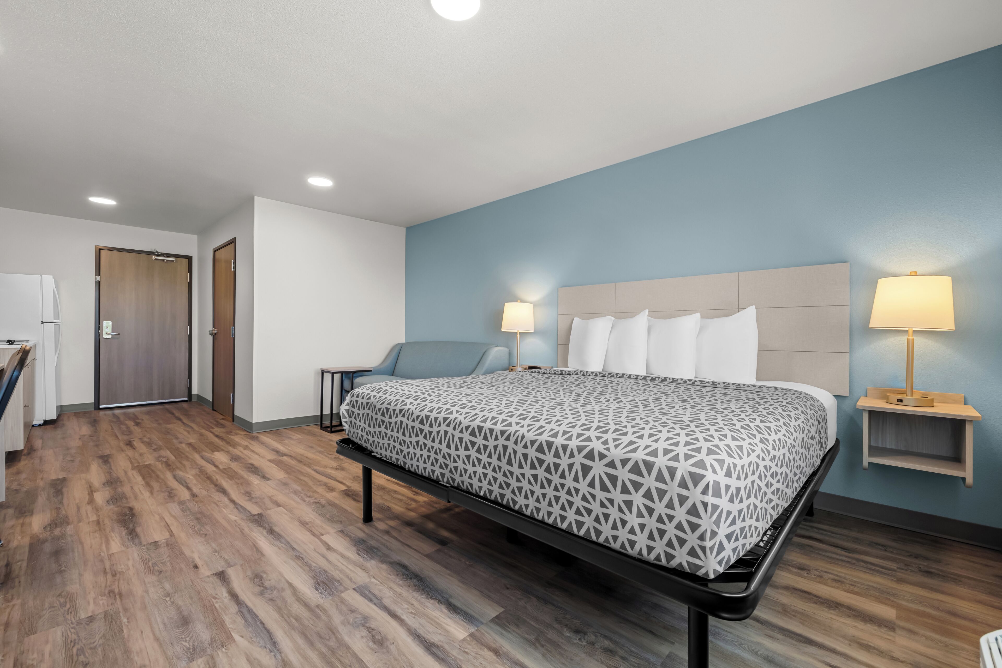 A hotel room with a bed, bedside lamps, a desk, and a chair.