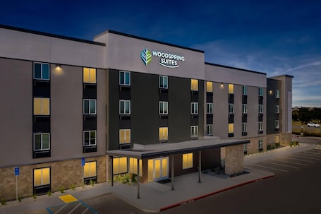 A modern hotel building with a flat roof, multiple windows, and a parking lot.. Woodspring Suites Manteca - Stockton South