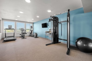 A gym with treadmills, an elliptical, a squat rack, and a large exercise ball. - Woodspring Suites Manteca - Stockton South (Manteca)