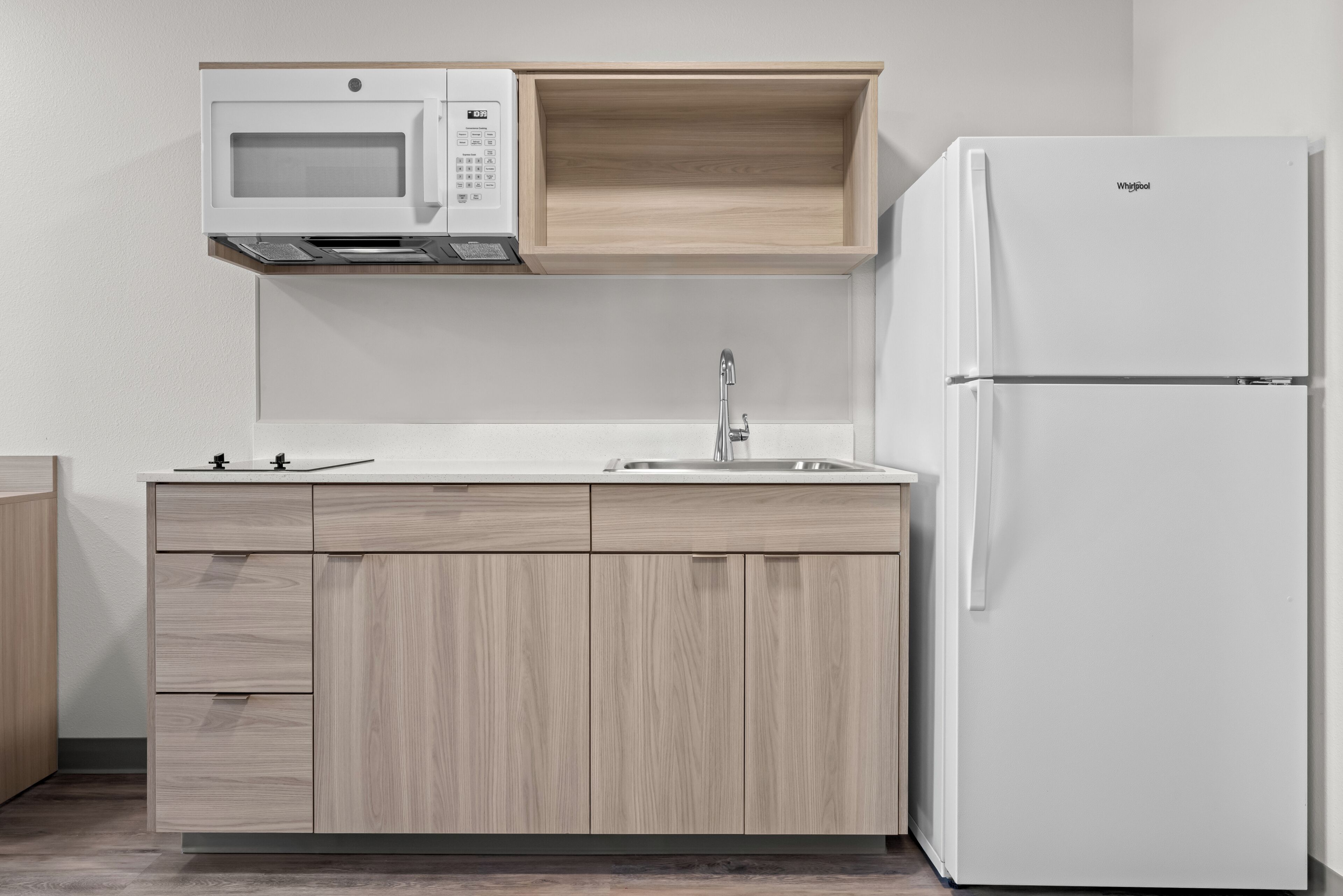 A kitchen with a built-in microwave, a sink, and a white refrigerator.