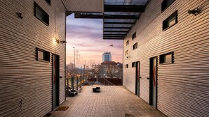 Een binnentuin met houten vloeren, metalen wanden en een uitzicht op een gebouw in de verte.